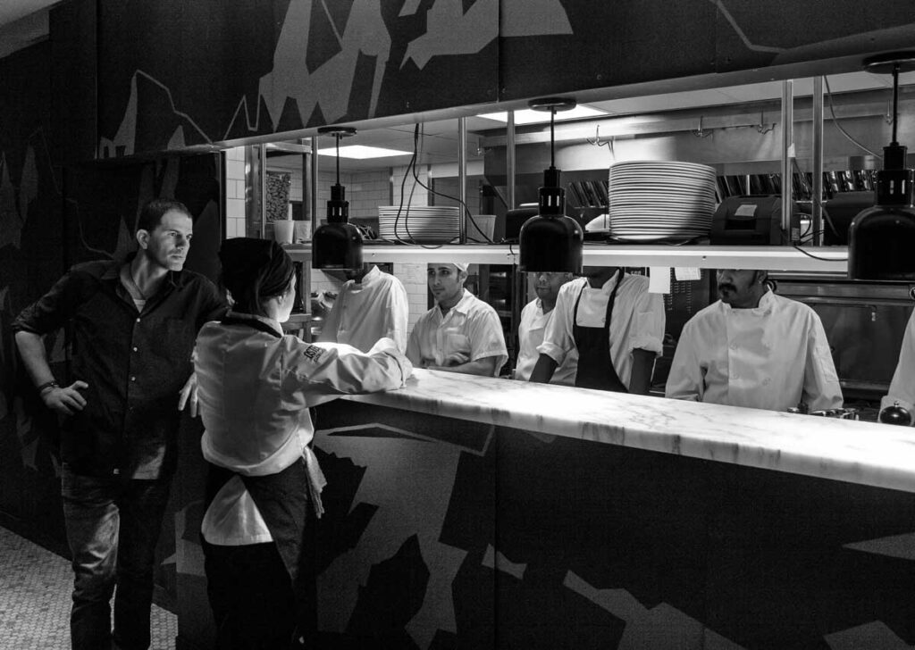 An image for Kyle Wyatt’s January-February 2026 review of “La Cucina di Terroni” by Cosimo Mammoliti, with Meredith Erickson, and The Seaside Café “Metropolis” by Antanas Sileika.